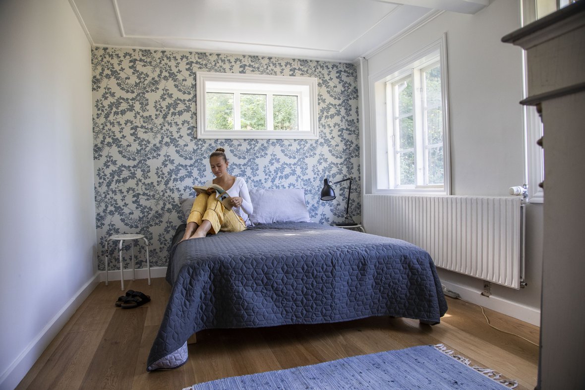 Smilla sidder og læser på seng i et af værelserne på Styrmandsgården