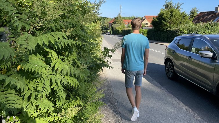 Mand går forbi uklippet hæk