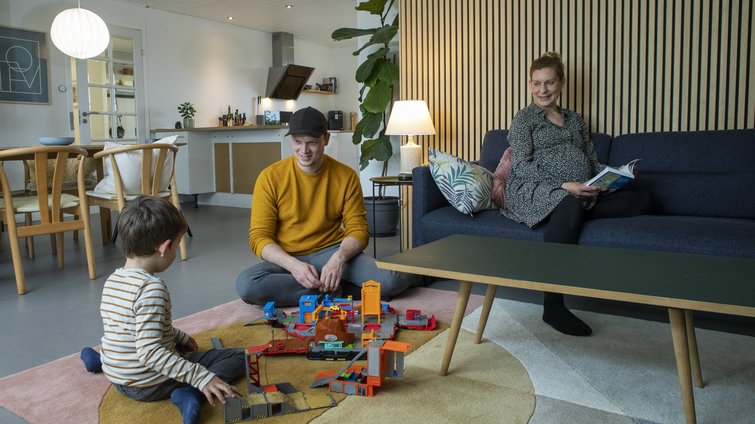 Mor, far og barn leger i stuen