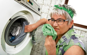 Kvinde aftørrer plastkanterne på vaskemaskine