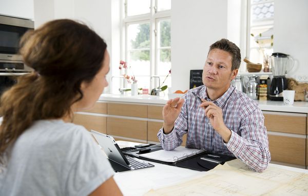 Kvinde taler med byggerådgiver ved spisebord Kvinde taler med byggerådgiver ved spisebord