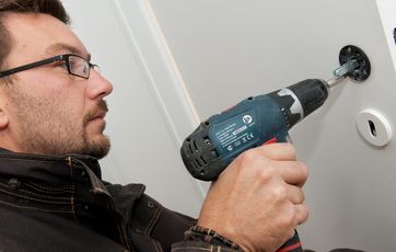 Hvis håndtaget har en løs roset, skal rosetten skrues fast med nye skruer. I ældre døre kan det være nødvendigt at spartle de gamle huller bag rosetten ud, før den skrues fast.