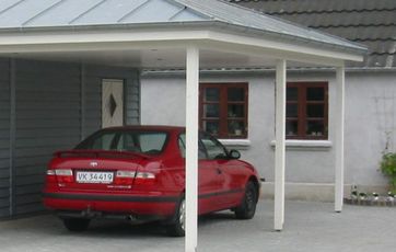 Rød bil i carport En bil i carporten får huset til at se beboet ud