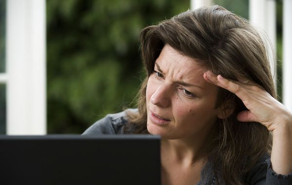 Kvinde kigger skeptisk på sin pc-skærm