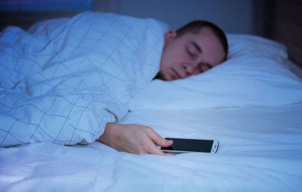 Mand sover med smartphone i hånden