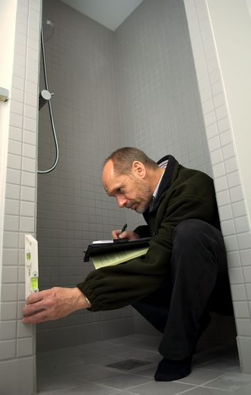 Mand tjekker, om vådrumssikring på badeværelse er i orden