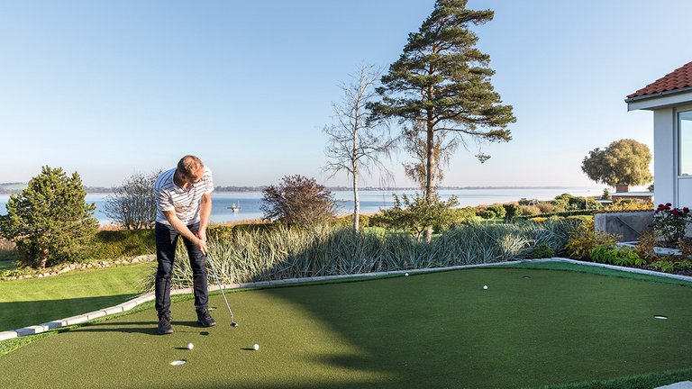 Udsigt til vand og egen golfbane med putting green i egen have
