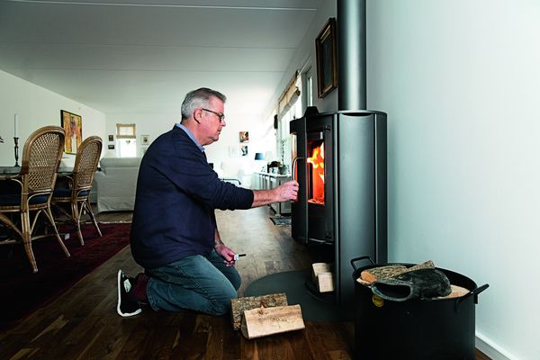 Røgsuger løser problem med røg fra brændeovn John Groser lukker glaslågen på sin brændeovn efter at have puttet brænde i den