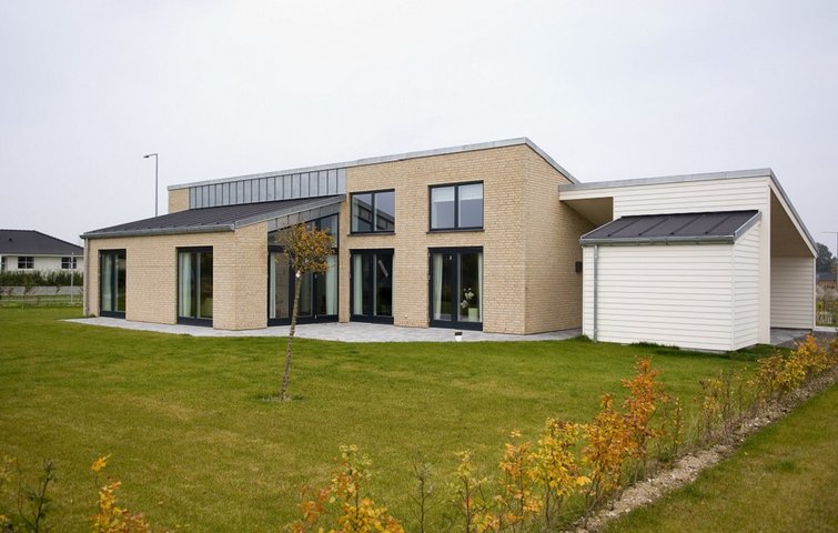 Morderne lavenergihus i gule teglsten med store vinduespartier.