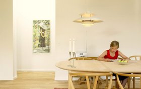 Pige sidder ved spisebord og læser.