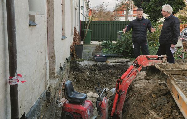 To byggerådgivere står foran hus, der er under renovering