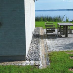 En rendesten af brosten sørger for, at terrassevandet ikke når ind til facaden