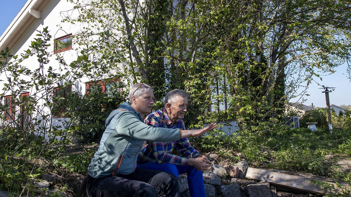 Par sidder foran hus og kigger ud over mark