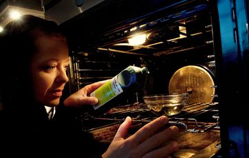 Kvinde hælder salmiakspiritus i en glasskål, der står i en ovn.