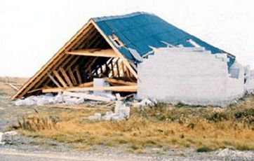 Resterne af hus, hvor taget er fløjet af og væggene væltet