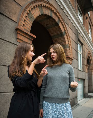 To unge kvinder foran bygningen, hvor de deler en lejlighed.