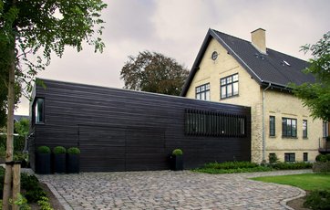 Detalje i facade, hvor der går et gitter af træ foran vinduerne.