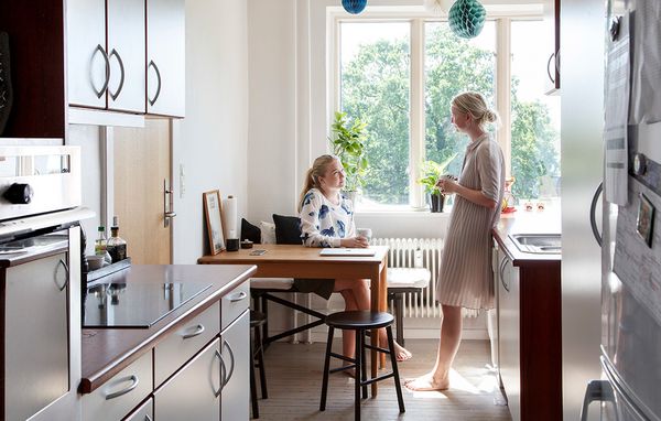To veninder, der bor sammen som roommates, snakker sammen i køkkenet i lejelejlighed.