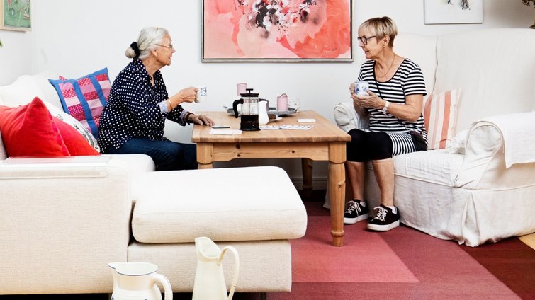 To kvinder siddende i sofaer taler sammen