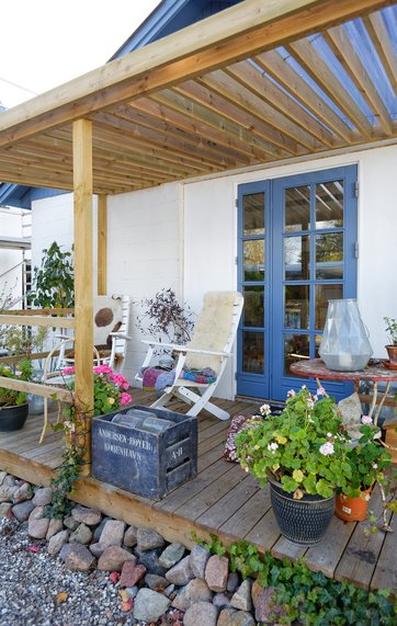 En overdækket træterrasse, der fungerer som shelter til sommerovernatninger.
