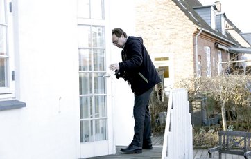 Mand inspicerer lister i havedør
