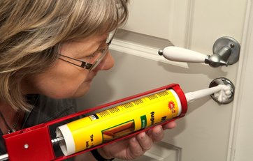 kvinde sprøjter acrylfugemasse ind i nøglehul