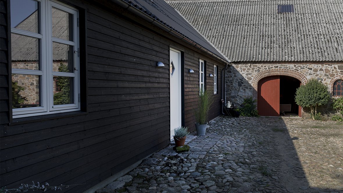 Bondehus i kampesten, gårdsplads med piksten og tilbygning i træ