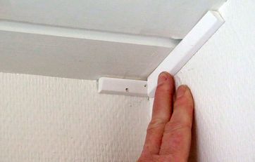 To lister mellem væg og et skråt loft bliver samlet i hjørnet.