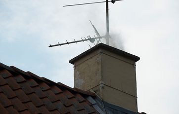 Røg fra brændeovn kommer op af skorsten