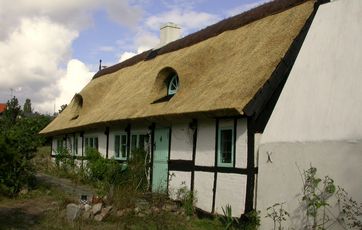 Landlig idyl med bindingsværk og stråtag.