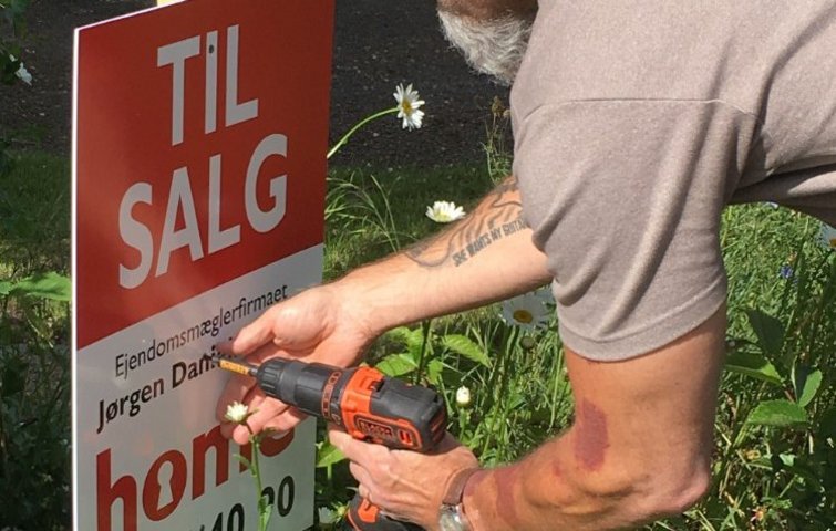 Ejendomsmægler sætter skilt op