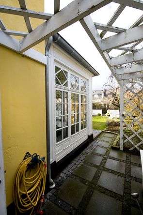 Fra orangeriets dobbeltfløjede glasdør er der direkte adgang til grønne omgivelser.