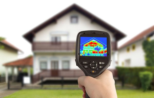 Et termografikamera holdes op foran et hus og viser, at der er utætheder i gavlen og ved nogle af vinduerne