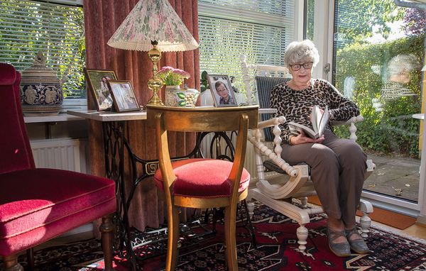84-årige Birgit Press sidder i en gyngestol og læser en bog.