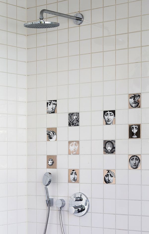 Fliseinspiration9 En bruseniche med hvide, kvadratiske fliser og enkelte kunstfliser med ansigter.