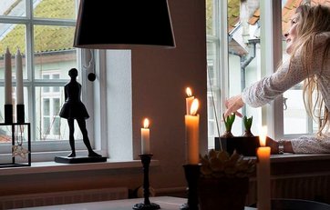 Kvinde åbner vinduet fordi hun har stearinlys tændt. Kvinde åbner vinduet fordi hun har stearinlys tændt.