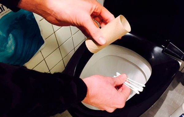 Mand skylder toiletpapirrulle og vatpinde i toilet. Mand skylder toiletpapirrulle og vatpinde i toilet.