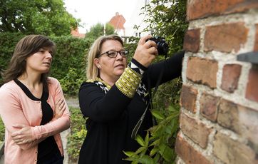 Fagekspert tager billede af skade i facade på hus.