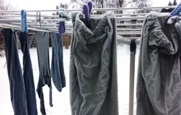 Tøj hænger på tørrestativ i frost.
