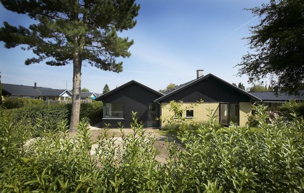 Gult parcelhus med tilbygning i sort træ