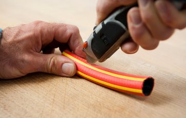 Hobbykniv skærer i haveslange.