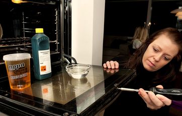 Kvinde i færd med at skrue glasset af en ovnlåge
