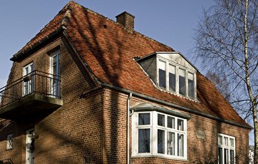 Klassisk murermestervilla med karnap og halvvalmet tag.