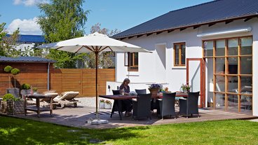 Anne Marie sidder i haven foran sit hus