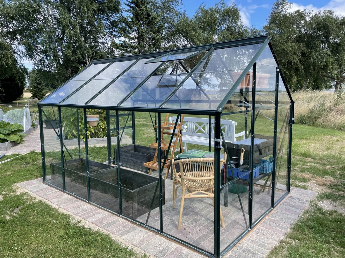 Klassisk drivhus med fliser, højbede og møbler